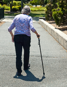 Elderly woman walking with aid of a cane