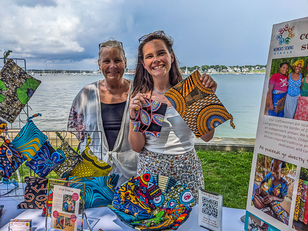 Two women at booth with brightly colored fabric articles