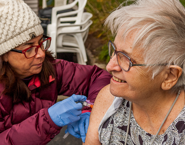 Nurse injects flu vaccination for elderly tenant