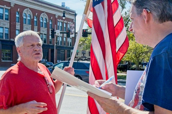 two men, one holding American flag